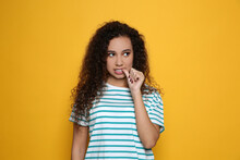 African-American Woman Biting Her Nails On Yellow Background