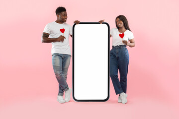 Couple showing white empty smartphone screen holding paper hearts