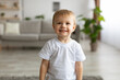 © Prostock-studio - Portrait of adorable toddler boy wearing white t-shirt and smiling, posing to camera in living room interior