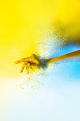 Wall Mural - Yellow and white. Female hand and explosion of colored, neoned powder on bright studio background with copy space. Magazine cover, wallpaper design