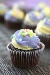 Wall Mural - Top view of yellow and purple easter cupcake on lined background