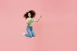 © ViDi Studio - Full size body length young curly latin woman 20s wears casual clothes sunglasses jump point aside on workspace area copy space mock up isolated on plain pastel light pink background studio portrait