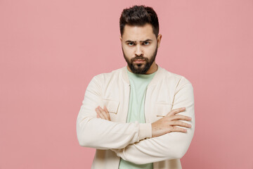 Canvas Print - Young sad offended frowning caucasian man 20s wearing trendy jacket shirt hold hands crossed folded look camera isolated on plain pastel light pink background studio portrait People lifestyle concept