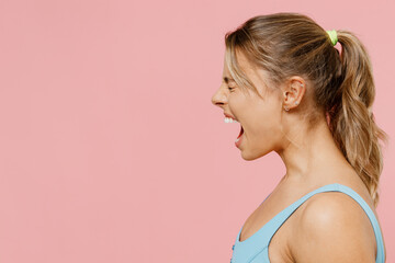 Side view profile young caucasian angry stressed woman 20s wear blue top tankshirt scream shout loud isolated on pastel plain light pink background studio portrait People lifestyle emotions concept