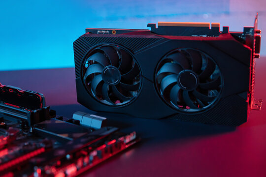 Modern graphic card lies on the desk next to motherboard