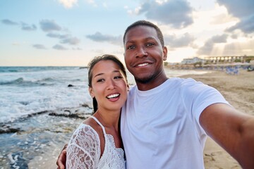 Happy couple in love taking selfie together on smartphone, on beach