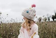 Portrait Of A Young Girl With Flowery Hat On Stood In A Flowery Field