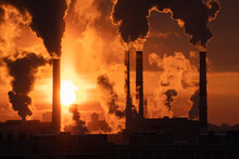 Chemical Factory Chimneys With Raising Smoke Against Red Sunset Sky In Winter City During Strong Frost. View From Afar Of Thermal Power Plant Pipes Emitting Hazardous Toxic Pollutants Into Atmosphere