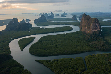 Aerial Drone footage flying over mangroves and lush rainforest in Phangnga bay Thailand The view is of mountainous islands and dramatic orange sunrise over the ocean