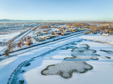 Aerial View Of Freezing Pond With Waterfowl And  Industrial Area Of Fort Collins, Colorado, With A Waste Water Treatment Plant, Winter Scenery At Sunset