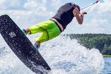Young Active Professional Athlete Jumping In The Air On A Wakeboard, Water Sports In The River 