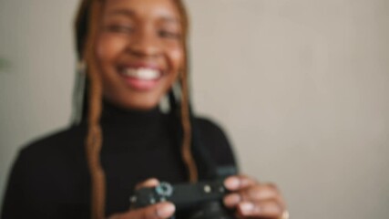 Wall Mural - Young female photographer smiling happily while taking pictures with a dslr camera. Cheerful young woman capturing images while standing in her home studio.