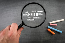 Hello. Text In Different World Languages. Magnifying Glass On A Dark Blackboard Background