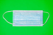Light Blue Surgical N95 Mask On Green Background, Antiviral Medical Mask For Protection Against Coronavirus. Surgical Protective Mask. Prevention Of The Spread Of Virus And Pandemic COVID 19
