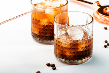 Black russian cocktail, alcohol drink with vodka, coffee liqueur and ice, white table background, bar tools, copy space