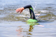 Swimmer swimming outdoor in nature with a green swimming cap and orange buoy