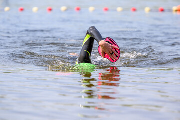 Swimmer swimming outdoor in nature with a green swimming cap and orange buoy