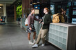 © LIGHTFIELD STUDIOS - Side view of smiling tourists with backpacks talking near reception in hotel