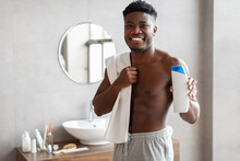 Black Guy Holding Shampoo Bottle Advertising Male Product In Bathroom
