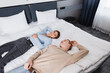 © LIGHTFIELD STUDIOS - High angle view of smiling couple lying on bed in hotel room