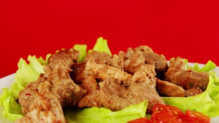 Wall Mural - Pieces of meat in a white plate on lettuce leaves and cherry tomatoes in a white plate on a red background.