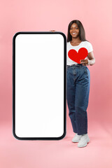 Black lady showing white empty smartphone screen holding paper heart