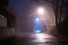 A Spooky Empty Country Road, With Street Lights. On An Atmospheric Foggy Winters Night. UK