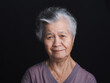 © meeboonstudio - An elderly Asian woman with short gray hair looking at the camera with a smile while standing on black background
