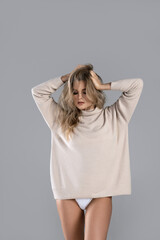 Poster - Young and sexy woman with blond hair wearing turtleneck jumper is posing in studio