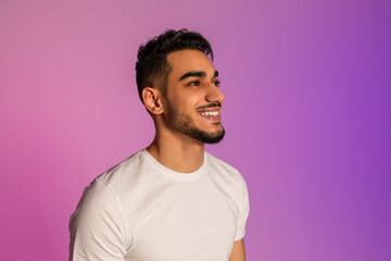 Poster - Handsome happy young Arab man in white t-shirt looking aside and smiling in neon light, copy space