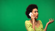 © LIGHTFIELD STUDIOS - shocked african american woman in hoop earrings talking on cellphone isolated on green
