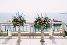 Lush Bouquets Of Flowers In Vases Stand On Small Columns On The Observation Deck Above The Sea