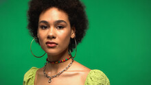 Disgusted African American Woman In Blouse And Hoop Earrings Isolated On Green
