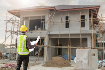 Wall Mural - young professional engineer in protective helmet and blueprints paper at the house building construction site