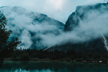 Wall Mural - Misty landscape with fir forest, lake and mountain in hipster vintage retro style. Dolomity italy