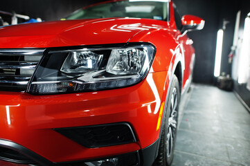 Headlight of nice and new orange sport suv car in modern garage.