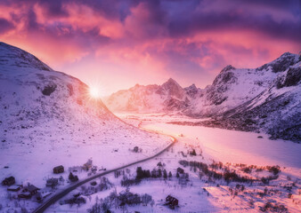 Wall Mural - aerial view of beautiful snowy mountains, road, houses and purple sky with pink clouds in winter at 