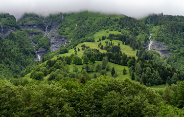 Wall Mural - Panoramic view on mountain waterfalls, green forests and apline meadows near Saint-Gervais-les-Bains, Savoy. France