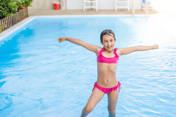 Wall Mural - happy little girl having fun in the pool in swimming suit.