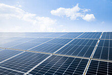 Photovoltaic Modules Of Huge Solar Panels With Clear Blue Sky And Sun On Background