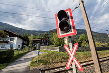 Level Crossing Sign, Called Crossbuck, Saltire Or Saint Andrews Cross, Standing On A Road Which Crosses A Railway Track In Germany Or Austria, Called Bahnubergang; In German, With Traffic Lights