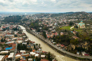 Wall Mural - View from drone of houses of georgian Kutaisi city on banks of Rioni river in spring day