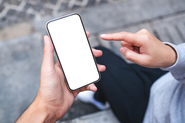 mockup image of a couple people holding and looking at the same mobile phone with blank black deskto