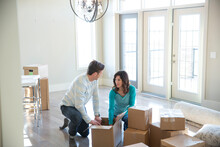 Couple Unpacking Cardboard Boxes In New Home
