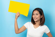 © suriya - Portrait of young girl holding a empty yellow speech bubble isolated on blue background