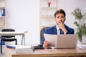 Young male employee unhappy with excessive work in the office