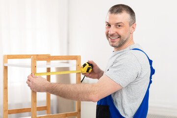 Mature Man Making Wooden Shelf Smiling To Camera Indoors