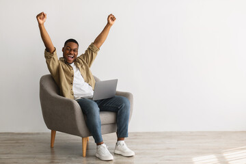 Canvas Print - Joyful Black Male With Laptop Shaking Fists On Gray Background