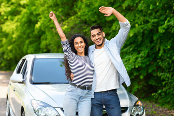 Emotional multiracial couple standing by nice auto