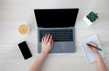 Aufkleber - Office workspace. Unrecognizable businesswoman working at laptop and writing notes in notebook, top view